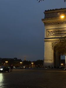 Moitié de l'arc de triomphe éclairée avec en fond la moitié de la tour Eiffel sous le brouillard